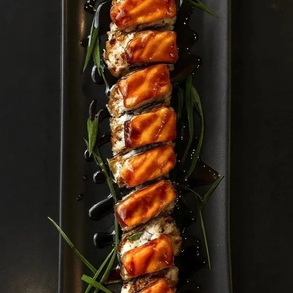 ROLL roll Roll's sushi rolls topped with glazed salmon, drizzled with dark sauce and garnished with chives.